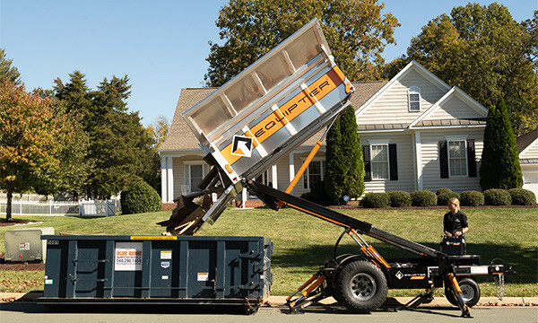 The Equipter 4000 dumping wood pieces into a roll away dumpster